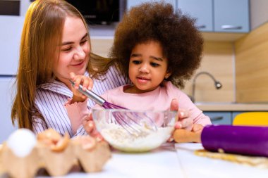 Polietnik aile bisküvi pişiriyor, kahvaltıyı evde birlikte hazırlıyorlar..