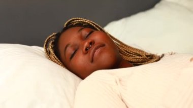 Afro-Amerikalı kadın yatak odasında uyurken gözlerini kapalı tutuyor..