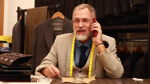 Giyimli Sakallı Olgun Yakışıklı Adam Atölyesinde Müşterisiyle Telefonla Konuşuyor — Stok video