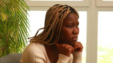 Endişeli kadın pencerenin yanında oturuyor ve yeşil bitki evde yalnız..