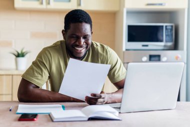 Latin kökenli serbest çalışan bir adam bilgisayarını kullanarak evde çalışıyor..