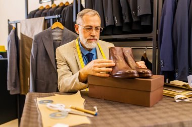 Bir atölyede el yapımı erkek ayakkabıları ve kemeri gösteren yaşlı bir ayakkabıcı..