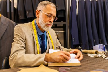 şık ve zengin takım elbiseli yaşlı yakışıklı adam atölyenin sahibi işiyle meşgul..