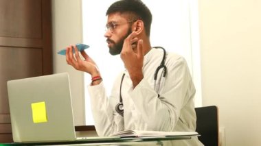 Neşeli Hintli doktor hastanedeki cep telefonundan sesli mesaj kaydediyor..