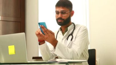 Neşeli Hintli doktor hastanedeki cep telefonundan sesli mesaj kaydediyor..