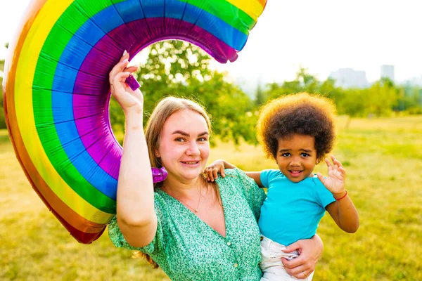happy multicultural race family playing with rainbow balloon outdoor.