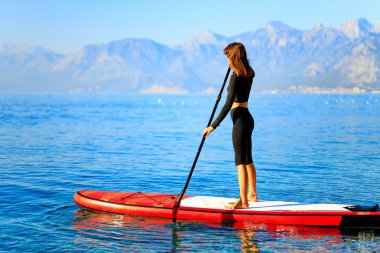 Woman standing on sup board and enjoying peace and quiet outdoors.