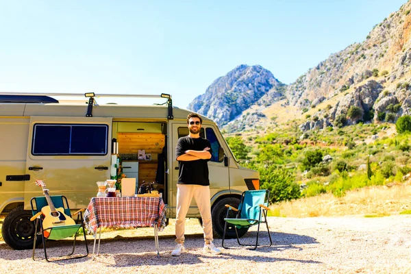 young man relaxing in rv, camping in a trailer mountain background.