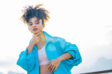 Mavi paltolu, afro saçlı, güzel, melez bir kadının portresini yakından çek. .