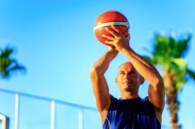 Açık havada basketbol oynayan Arap bir sporcu..