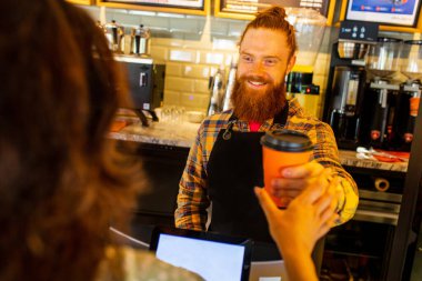 Profesyonel barista, kızıl saçlı, sakallı, siyah önlüklü, kafede çalışan genç bir adam..
