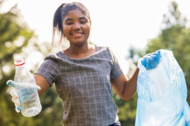 Afrika kökenli Amerikalı gönüllüler güneşli yaz parkında plastik çöp topluyorlar..