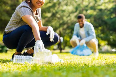 Afrika kökenli Amerikalı gönüllüler güneşli yaz parkında plastik çöp topluyorlar..