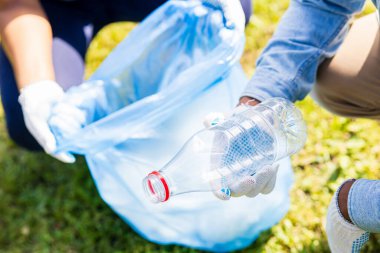 Afrika kökenli Amerikalı gönüllüler güneşli yaz parkında plastik çöp topluyorlar..