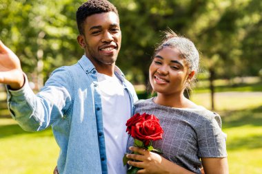 Güneşli bir günde yaz parkında romantik piknikte gülümseyen Afrikalı çift..