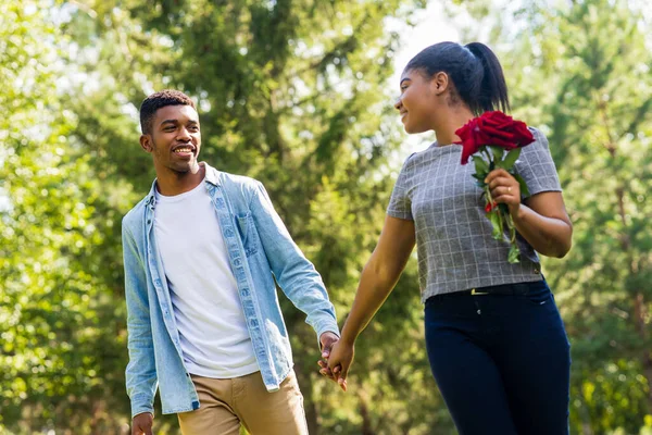 Güneşli bir günde yaz parkında romantik piknikte gülümseyen Afrikalı çift..