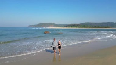 Kıyı şeridi sahili üzerinde yürüyen bir couole ve Goa 'nın deniz manzaralı insansız hava aracı..