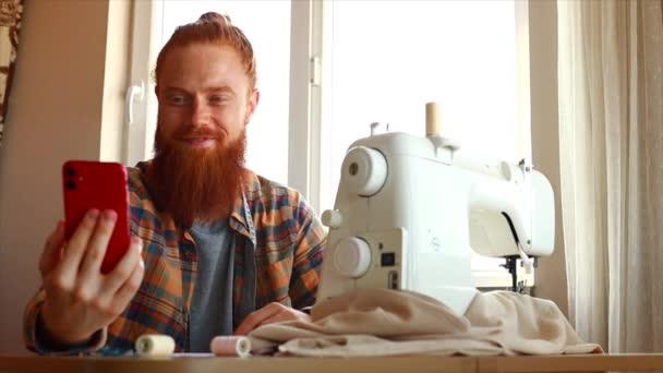 Handsome Redhaired Man Long Beard Sews Sewing Machine Home Studio — Stock Video