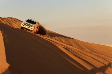 Beyaz araba Rub al Khali Çölü 'nde, Abu Dabi' deki Boş Bölge 'de gün batımında Birleşik Arap Emirlikleri' nde sürüyor..