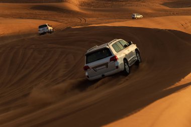 Beyaz araba Rub al Khali Çölü 'nde, Abu Dabi' deki Boş Bölge 'de gün batımında Birleşik Arap Emirlikleri' nde sürüyor..