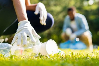 Afrika kökenli Amerikalı gönüllüler güneşli yaz parkında plastik çöp topluyorlar..