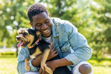 Latin Amerikalı adam güneşli bir günde sevimli köpeğiyle çimlerin üzerinde çimlerin üzerinde yürüyor..