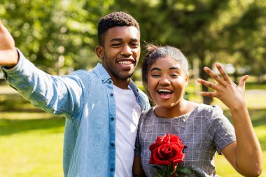 Güneşli bir günde yaz parkında romantik piknikte gülümseyen Afrikalı çift..