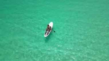 Maldivler 'in turkuaz sularında beyaz bir yatak üzerinde bir kadının hava manzarası..