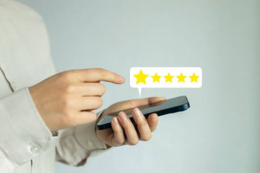 Bir kadın cep telefonu tutuyor ve beş yıldızlı bir dereceye işaret ediyor.