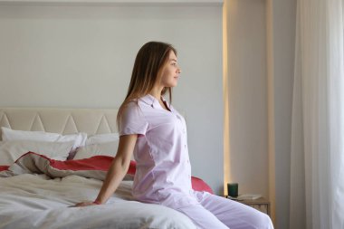 Genç ve güzel bir kadın sabah uyandıktan sonra yatağında geriniyor. Yüzünde tatmin edici bir ifade olan uykulu esmer kadın. Sağlıklı uyku alışkanlıkları konsepti. Kapat, kopyala boşluk, arkaplan.