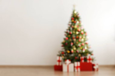 Beyaz duvar zemininde bokeh efektli yumuşak sarı ışıklarla süslenmiş Noel ağacını bulanıklaştırdım. Kapat, metin için boşluk kopyala.