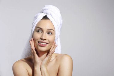 Banyo yaptıktan sonra saç havlusu sarılı genç bir kadının stüdyo portresi. Kapat, kopyala alanı, izole edilmiş gri arkaplan.