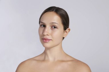 Uzun siyah saçlı, at kuyruklu ve temiz yüzlü güzel bir kadının stüdyo portresi. Kapat, kopyala alanı, izole edilmiş gri arkaplan.