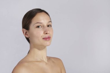 Uzun siyah saçlı, at kuyruklu ve temiz yüzlü güzel bir kadının stüdyo portresi. Kapat, kopyala alanı, izole edilmiş gri arkaplan.