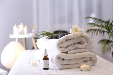 Masaj odası konsepti. Masaj masasındaki kozmetik işlemler için taş terapisi özellikleri. Spa salonu için sembolik nesneler. Kapat, metin, üst görünüm ve arkaplan için boşluk kopyala.