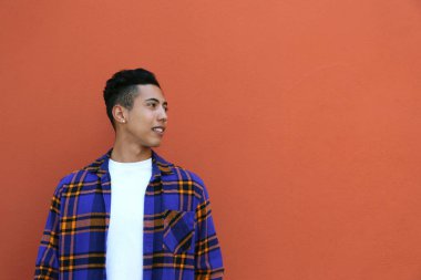 İspanyol kökenli genç adam turuncu duvarın üzerinde renkli flanel gömlek giyiyor. Metin için boşluk kopyala, kapat, arkaplan.