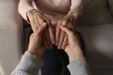 Yaşlı kadın ve kadın sosyal hizmet görevlisinin el ele tutuşması. Farklı yaşlardaki kadınlar birbirlerini teselli ediyorlar. Kapat, arkaplan, kopyala.