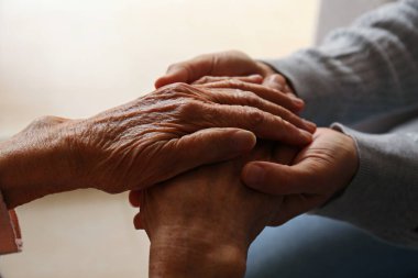 Yaşlı kadın ve kadın sosyal hizmet görevlisinin el ele tutuşması. Farklı yaşlardaki kadınlar birbirlerini teselli ediyorlar. Kapat, arkaplan, kopyala.