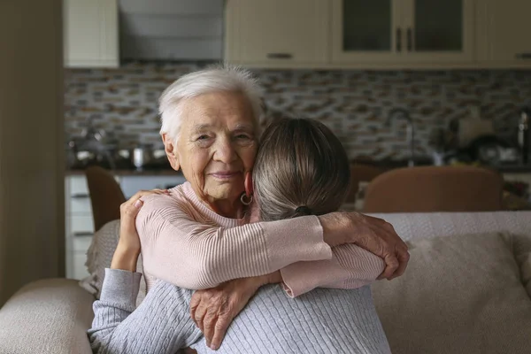 Grandmother and granddaughter hugging in the living room. Two adult women of different age. Family values concept. Close up, copy space, background.