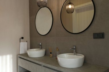 Modern banyo, iki lavabo, yuvarlak aynalar, havlular ve tuvalet malzemeleri. Çağdaş minimalizm tarzında beyaz seramik lavabolar. Boşluğu kopyala, arkaplan.