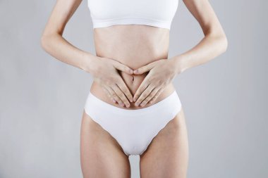 Karın ağrısı yüzünden karnına dokunan bir kadın resmi. Karın ağrısı çeken tanınmayan bir kadın. Kapat, kopyala boşluk, arkaplan.