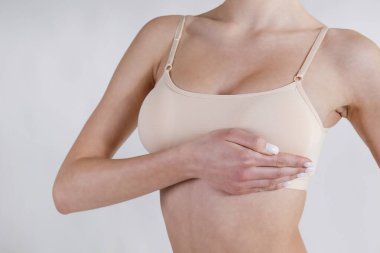 Tanımlanamayan bir kadının stüdyo çekimi, göğüslerine bastırma, göğüs kanseri belirtilerini kontrol etme. Kapat, kopyala boşluk, beyaz arkaplan.