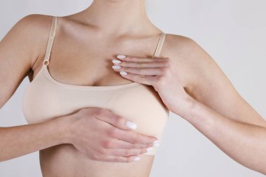 Tanımlanamayan bir kadının stüdyo çekimi, göğüslerine bastırma, göğüs kanseri belirtilerini kontrol etme. Kapat, kopyala boşluk, beyaz arkaplan.