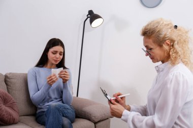 Terapi seansı konsepti. Genç bir kadın ofisinde yetişkin bir kadın psikiyatristten profesyonel yardım alıyor. Kapat, kopyala boşluk, arkaplan.