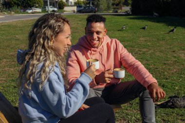 Genç çift parkta kahve içiyor..