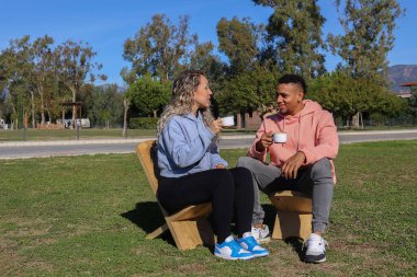 Genç çift parkta kahve içiyor..