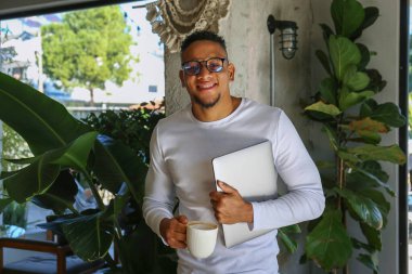 Kahve dükkanında bir fincan kapuçino içen genç adam..