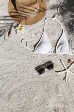 Yaz titreşimleri. Hasır şapka, mayo ve güneş gözlüğü kumlu bir plajda düzlük, fotokopi alanı, üst manzara, arka plan..