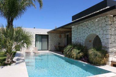 Güneşli bir günde, bir kır evinin arka bahçesindeki boş bir havuzun huzurlu görüntüsü. Kapat, boşluğu kopyala, arkaplanda dağlar.