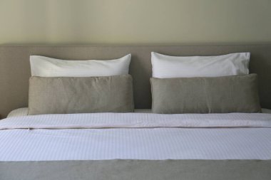 Yatak başlıklı, temiz ve ütülenmiş çarşaflı ve kabarık yastıklı yeni yapılmış kral yataklı bir otel odası. Kapat, metin için boşluk kopyala.